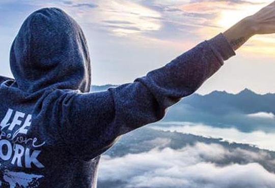 Female solo traveller with arms out at Mount Batur volcano