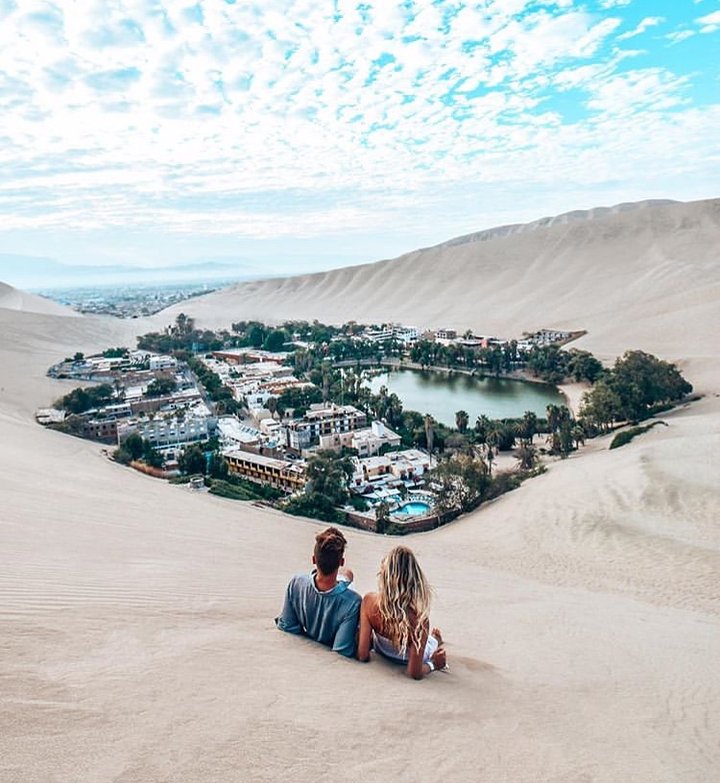 couple sitting in the sand dunes of huacachina peru peru hop discount code